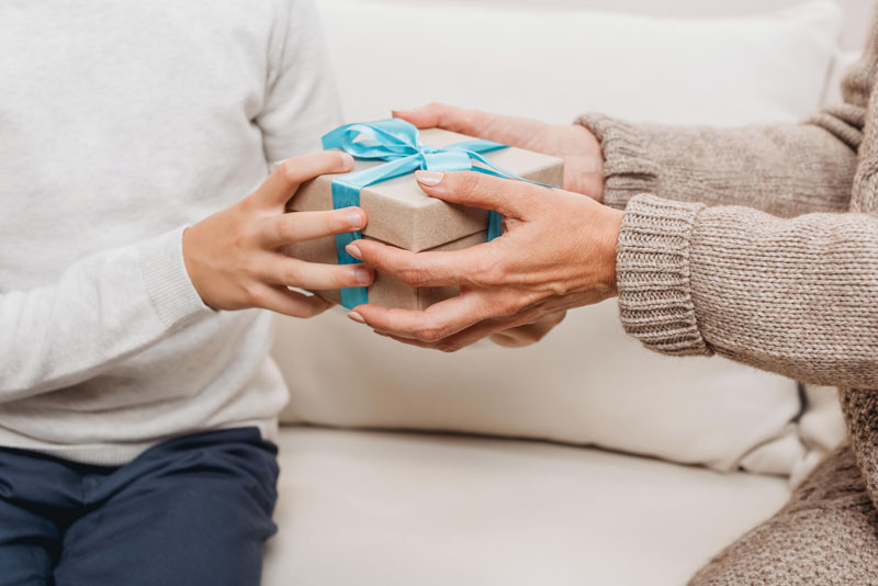 ludzie przekazują sobie pudełko z prezentem voucher do hotelu i apartamentów w krakowie